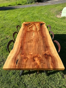 Custom solid timber slab dining table photographed outdoors on grass, made to order in New Zealand