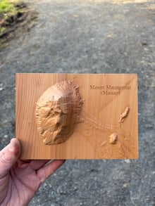 Timber terrain model of Mount Maunganui (Mauao) held in hand