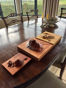 Three timber terrain models of Whale Island, Mount Maunganui and Mayor Island on a dining table